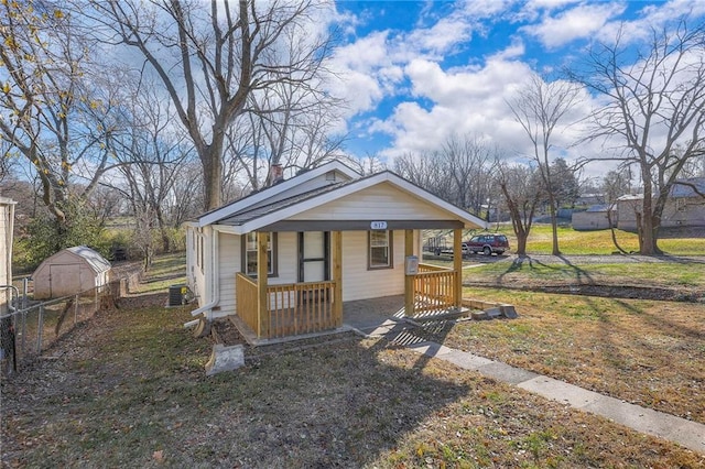 bungalow featuring covered porch, a front yard, and central air condition unit