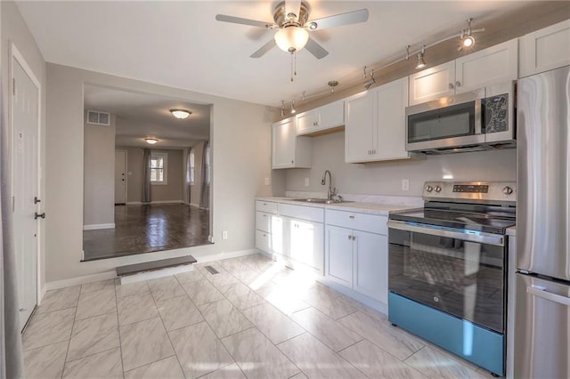 kitchen with white cabinetry, sink, ceiling fan, and stainless steel appliances