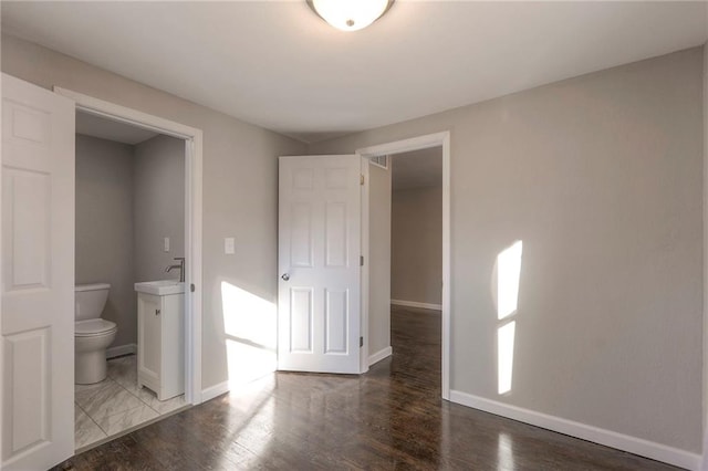 unfurnished bedroom with ensuite bath, sink, and hardwood / wood-style flooring