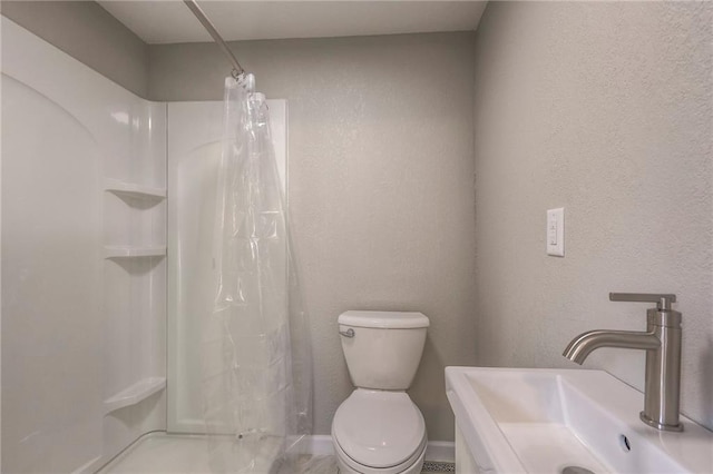 bathroom with a shower with shower curtain, toilet, and sink