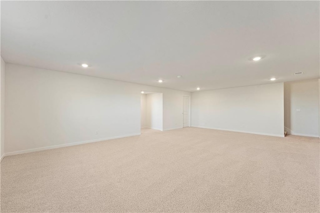 empty room with light carpet, baseboards, and recessed lighting