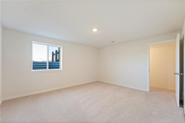 spare room featuring baseboards, recessed lighting, and light colored carpet