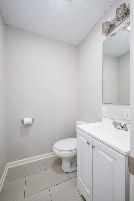 bathroom with tile patterned flooring, vanity, a textured ceiling, and toilet