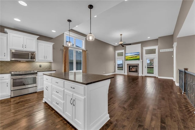 kitchen with white cabinetry, dark hardwood / wood-style flooring, a kitchen island, and stainless steel appliances