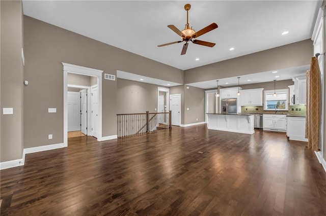 unfurnished living room featuring dark hardwood / wood-style floors, ceiling fan, and sink