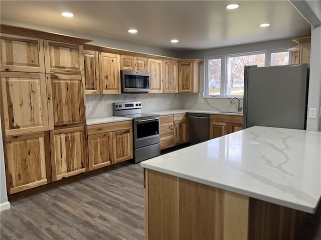 kitchen featuring light stone counters, sink, appliances with stainless steel finishes, and dark wood-type flooring