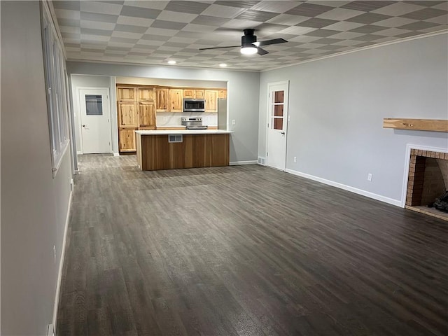 kitchen featuring ceiling fan, a fireplace, appliances with stainless steel finishes, dark hardwood / wood-style flooring, and kitchen peninsula