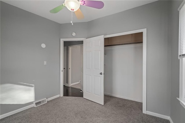 unfurnished bedroom with ceiling fan, dark carpet, and a closet