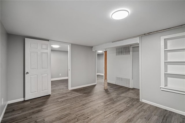 basement with built in shelves and dark wood-type flooring