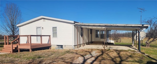 rear view of house featuring a wooden deck, a carport, and a yard