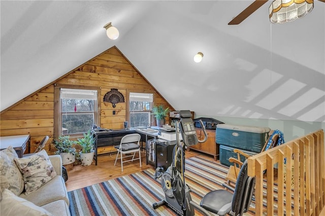 interior space with light wood-type flooring, ceiling fan, lofted ceiling, and wood walls