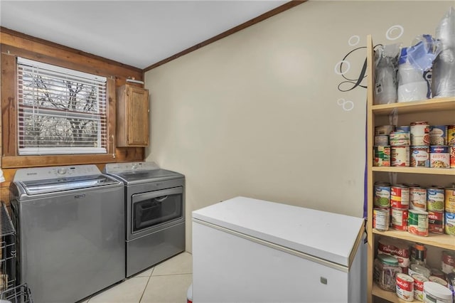 washroom with cabinets, light tile patterned floors, ornamental molding, and washing machine and clothes dryer