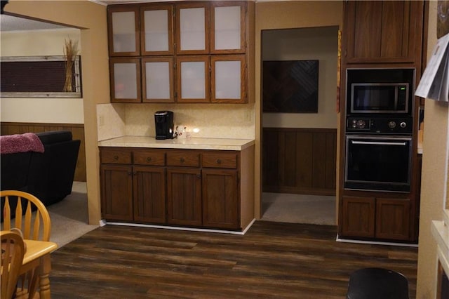 kitchen with black oven, wood walls, dark hardwood / wood-style flooring, and decorative backsplash