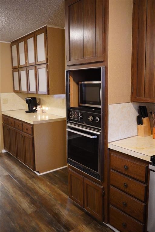 kitchen featuring black oven, dark wood-type flooring, and a textured ceiling