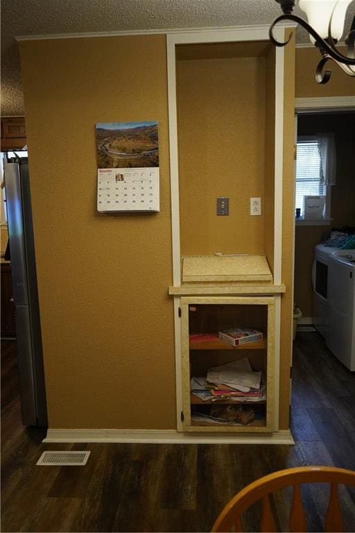 interior space with a chandelier, a textured ceiling, dark hardwood / wood-style floors, and washer and dryer