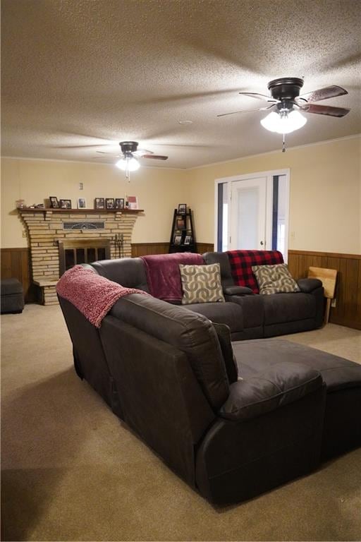 carpeted living room featuring a textured ceiling, a stone fireplace, ceiling fan, and wood walls