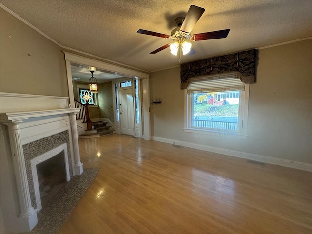 unfurnished living room featuring a fireplace, a textured ceiling, hardwood / wood-style flooring, and ornamental molding