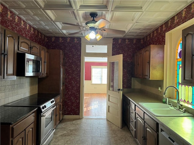 kitchen featuring coffered ceiling, dark brown cabinetry, stainless steel appliances, ceiling fan, and sink