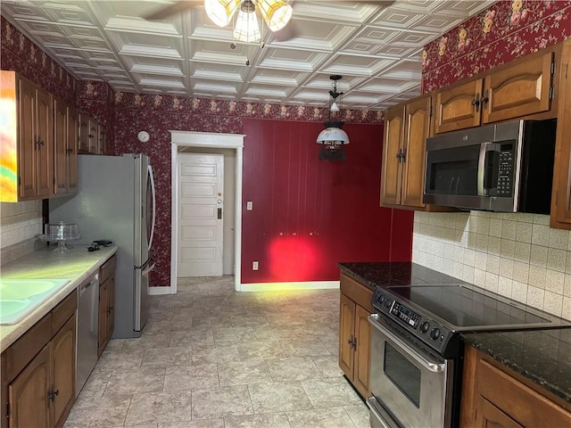 kitchen featuring backsplash, dark stone countertops, ceiling fan, and appliances with stainless steel finishes