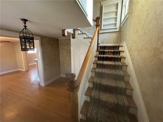 stairway featuring crown molding and wood-type flooring