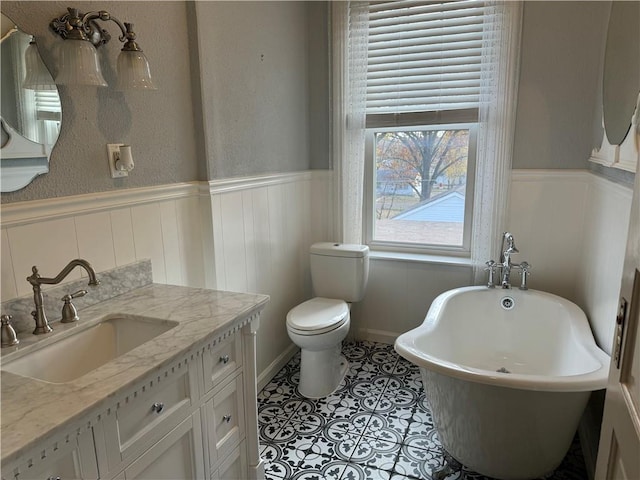 bathroom featuring tile patterned flooring, vanity, toilet, and a tub