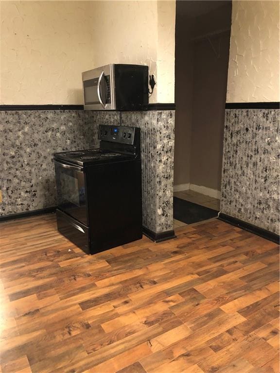 kitchen featuring black range with electric cooktop and hardwood / wood-style flooring