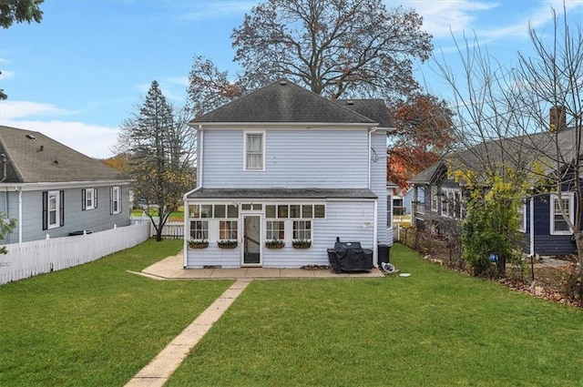 back of house featuring a lawn, a sunroom, and a patio area