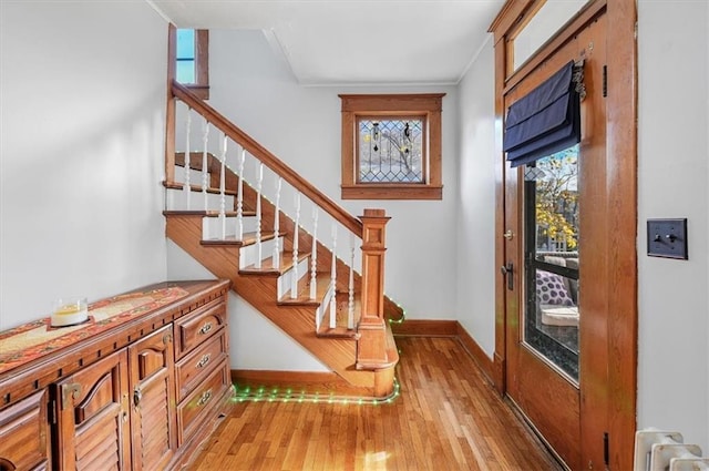 entryway with baseboards, stairway, a healthy amount of sunlight, and light wood-style flooring