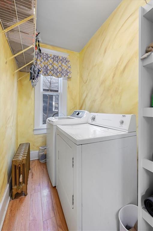 washroom featuring wood finished floors, laundry area, independent washer and dryer, radiator, and baseboards