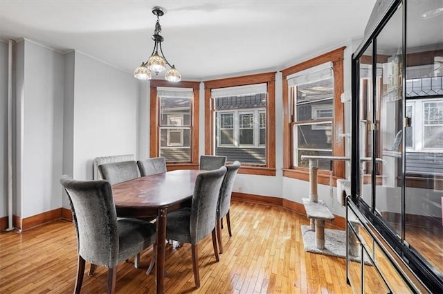 dining room with ornamental molding, light wood-style flooring, and baseboards
