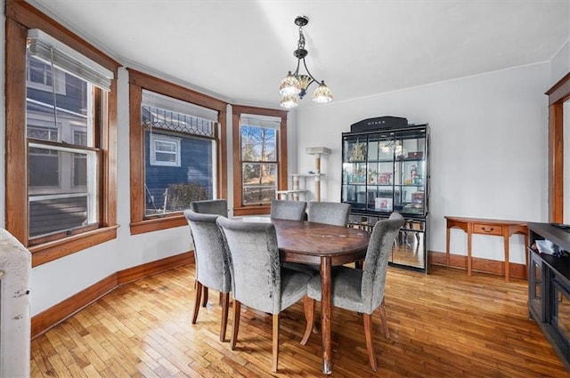 dining room featuring baseboards, a notable chandelier, crown molding, and wood-type flooring