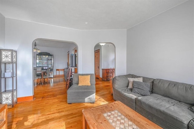 living room with arched walkways and light wood-style flooring