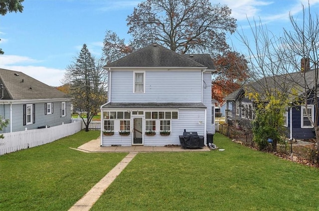 rear view of property with a lawn, a shingled roof, a sunroom, and fence