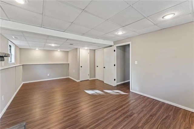 basement featuring a paneled ceiling and dark hardwood / wood-style flooring