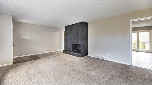 unfurnished living room featuring carpet floors, a textured ceiling, and a brick fireplace