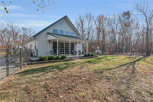 back of property with a yard and covered porch