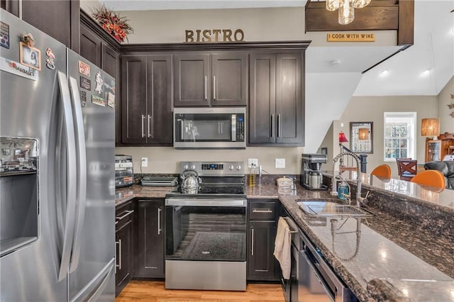 kitchen featuring sink, dark stone countertops, appliances with stainless steel finishes, light hardwood / wood-style floors, and dark brown cabinetry