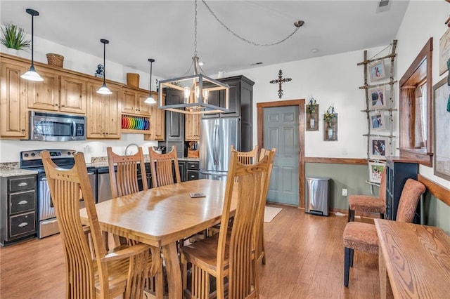 dining space with light hardwood / wood-style floors and an inviting chandelier