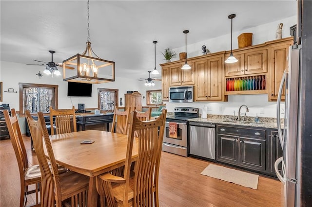 kitchen with sink, decorative light fixtures, light hardwood / wood-style floors, light stone counters, and stainless steel appliances