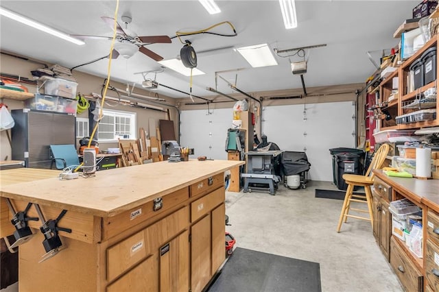 garage featuring a workshop area, a garage door opener, and ceiling fan