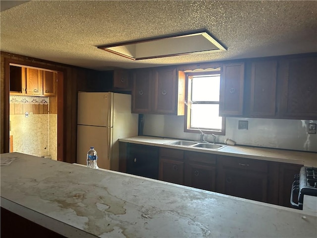 kitchen featuring a textured ceiling, black range, white fridge, and sink