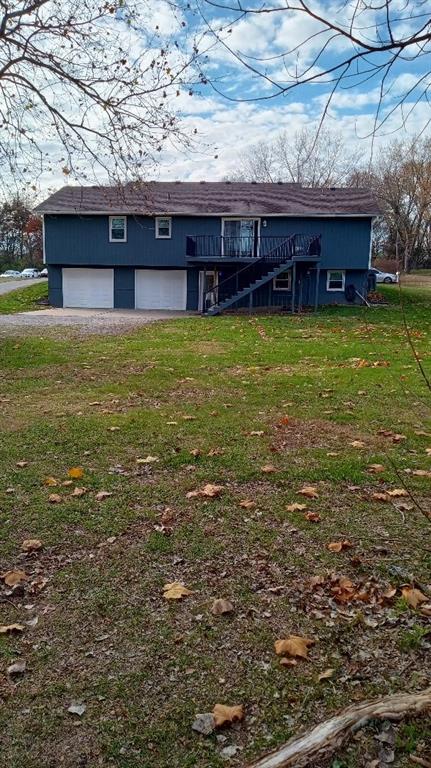 back of property with a garage, a deck, and a yard