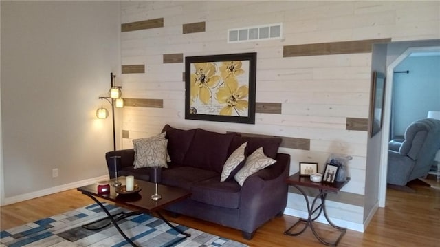 living room with hardwood / wood-style floors and wood walls