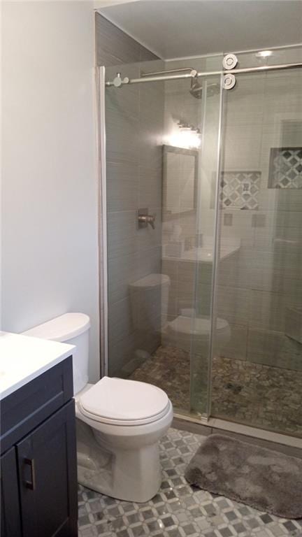 bathroom with a shower with door, vanity, and toilet