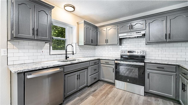 kitchen with gray cabinetry, sink, dark hardwood / wood-style floors, decorative backsplash, and appliances with stainless steel finishes