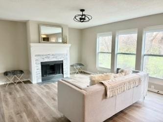 living room featuring a stone fireplace, a wealth of natural light, and light wood-type flooring