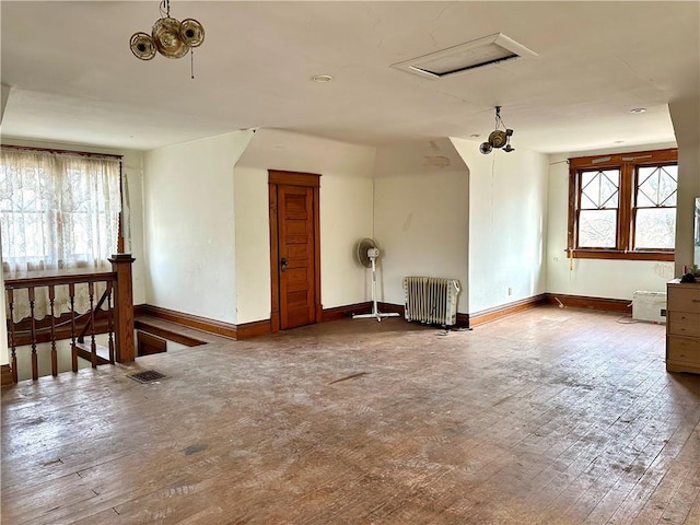 empty room featuring plenty of natural light, wood-type flooring, and radiator