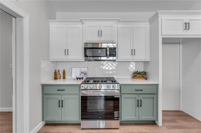 kitchen featuring white cabinetry, decorative backsplash, light wood-type flooring, and appliances with stainless steel finishes