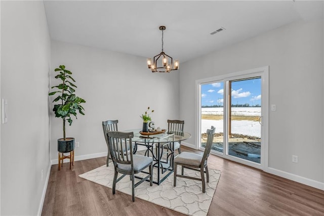 dining room with a water view, a notable chandelier, and hardwood / wood-style flooring