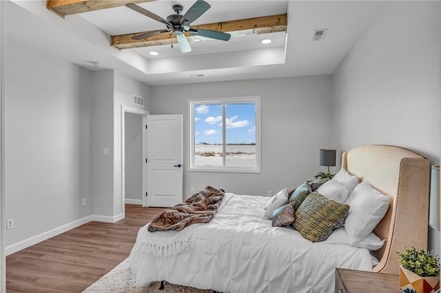 bedroom with ceiling fan, a raised ceiling, beamed ceiling, and light wood-type flooring